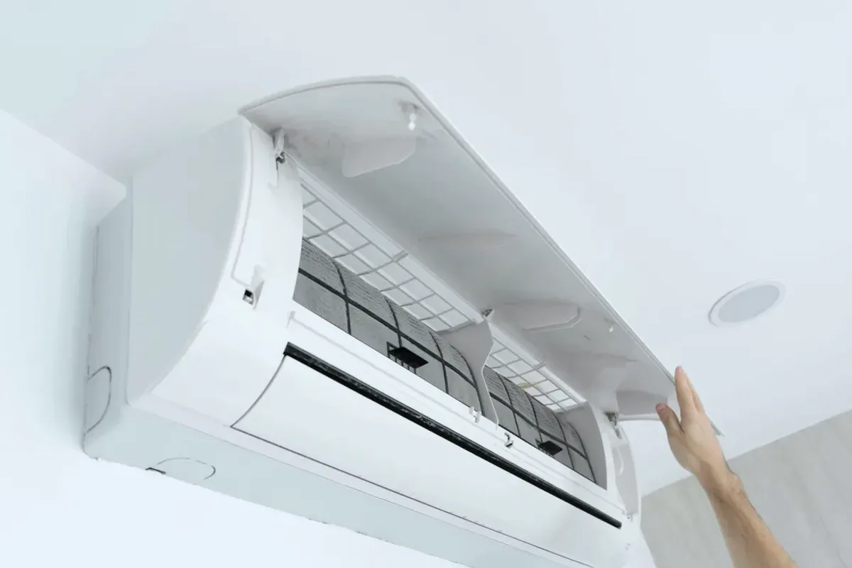 Hand opening the cover of a wall-mounted ductless air conditioner